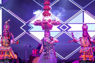 Bikaner, Rajasthan, Hindistan - 14 Ocak 2023: Güzel Hintli kadın sanatçı, geleneksel kıyafetlerle bikaner deve festivali sırasında kafasında çamur tencereleriyle geleneksel halk dansı yapıyor.
