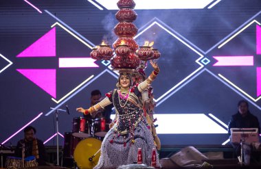 Bikaner, Rajasthan, Hindistan - 14 Ocak 2023: Güzel Hintli kadın sanatçı, geleneksel kıyafetlerle bikaner deve festivali sırasında kafasında çamur tencereleriyle geleneksel halk dansı yapıyor.