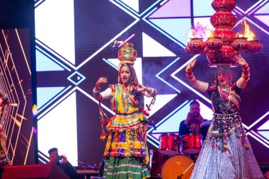 Bikaner, Rajasthan, Hindistan - 14 Ocak 2023: Güzel Hintli kadın sanatçı, geleneksel kıyafetlerle bikaner deve festivali sırasında kafasında çamur tencereleriyle geleneksel halk dansı yapıyor.