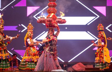 Bikaner, Rajasthan, Hindistan - 14 Ocak 2023: Güzel Hintli kadın sanatçı, geleneksel kıyafetlerle bikaner deve festivali sırasında kafasında çamur tencereleriyle geleneksel halk dansı yapıyor.