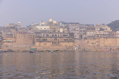 Varanasi, Uttar Pradesh, Hindistan - 20 Ocak 2024: Varanasi 'deki nehir çetelerinin yakınındaki ghatların mimari görüşü ve tapınakları. Ganga nehrinde yüzen tekneden binaların görüntüsü.