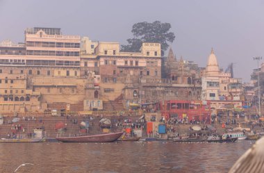 Varanasi, Uttar Pradesh, Hindistan - 20 Ocak 2024: Varanasi 'deki nehir çetelerinin yakınındaki ghatların mimari görüşü ve tapınakları. Ganga nehrinde yüzen tekneden binaların görüntüsü.