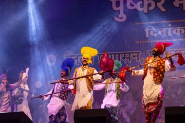 Bikaner, Rajasthan, Hindistan - 14 Ocak 2023: Punjab 'dan bir grup Punjab sanatçısı bikaner deve festivalinde geleneksel renkli elbiseler içinde bhangra dansı yapıyorlar.