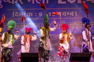 Bikaner, Rajasthan, Hindistan - 14 Ocak 2023: Punjab 'dan bir grup Punjab sanatçısı bikaner deve festivalinde geleneksel renkli elbiseler içinde bhangra dansı yapıyorlar.