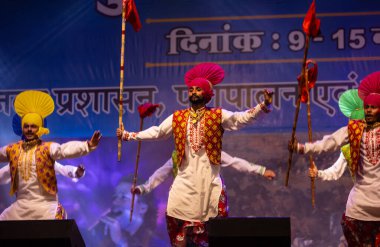 Bikaner, Rajasthan, Hindistan - 14 Ocak 2023: Punjab 'dan bir grup Punjab sanatçısı bikaner deve festivalinde geleneksel renkli elbiseler içinde bhangra dansı yapıyorlar.
