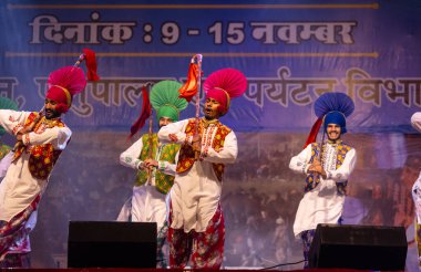 Bikaner, Rajasthan, Hindistan - 14 Ocak 2023: Punjab 'dan bir grup Punjab sanatçısı bikaner deve festivalinde geleneksel renkli elbiseler içinde bhangra dansı yapıyorlar.