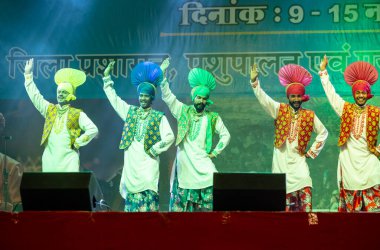 Bikaner, Rajasthan, Hindistan - 14 Ocak 2023: Punjab 'dan bir grup Punjab sanatçısı bikaner deve festivalinde geleneksel renkli elbiseler içinde bhangra dansı yapıyorlar.