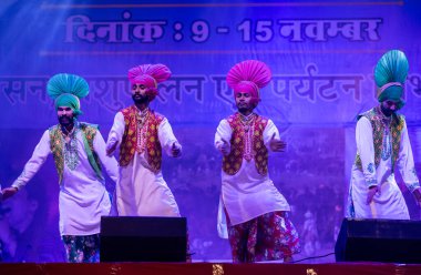 Pushkar, Rajasthan, Hindistan - 11 Kasım 2024: Bhangra, Sih erkek sanatçılar grubu renkli etnik elbiseler içinde bhangra dansı yapıyorlar..