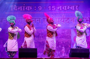 Pushkar, Rajasthan, Hindistan - 11 Kasım 2024: Bhangra, Sih erkek sanatçılar grubu renkli etnik elbiseler içinde bhangra dansı yapıyorlar..