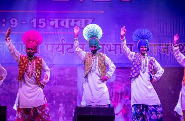 Pushkar, Rajasthan, Hindistan - 11 Kasım 2024: Bhangra, Sih erkek sanatçılar grubu renkli etnik elbiseler içinde bhangra dansı yapıyorlar..