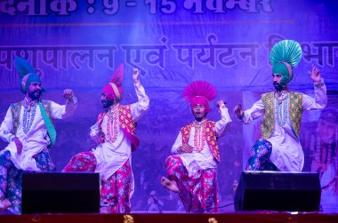 Pushkar, Rajasthan, Hindistan - 11 Kasım 2024: Bhangra, Sih erkek sanatçılar grubu renkli etnik elbiseler içinde bhangra dansı yapıyorlar..