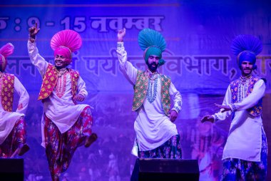Pushkar, Rajasthan, Hindistan - 11 Kasım 2024: Bhangra, Sih erkek sanatçılar grubu renkli etnik elbiseler içinde bhangra dansı yapıyorlar..