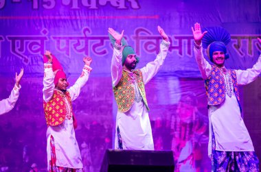 Puşkar, Rajasthan, Hindistan - 11 Kasım 2024: Bhangra, Bhangra grubu, açık hava kültür gecesi renkli etnik elbiseler içinde bhangra dansı yapıyor.
