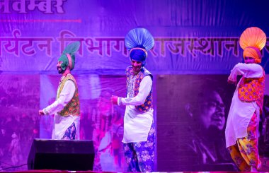 Puşkar, Rajasthan, Hindistan - 11 Kasım 2024: Bhangra, Bhangra grubu, açık hava kültür gecesi renkli etnik elbiseler içinde bhangra dansı yapıyor.