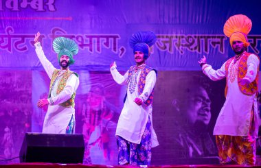 Puşkar, Rajasthan, Hindistan - 11 Kasım 2024: Bhangra, Bhangra grubu, açık hava kültür gecesi renkli etnik elbiseler içinde bhangra dansı yapıyor.