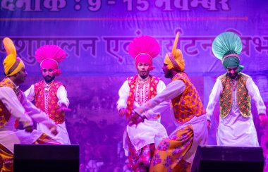 Puşkar, Rajasthan, Hindistan - 11 Kasım 2024: Bhangra, Bhangra grubu, açık hava kültür gecesi renkli etnik elbiseler içinde bhangra dansı yapıyor.