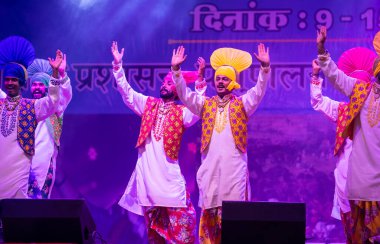 Puşkar, Rajasthan, Hindistan - 11 Kasım 2024: Bhangra, Bhangra grubu, açık hava kültür gecesi renkli etnik elbiseler içinde bhangra dansı yapıyor.