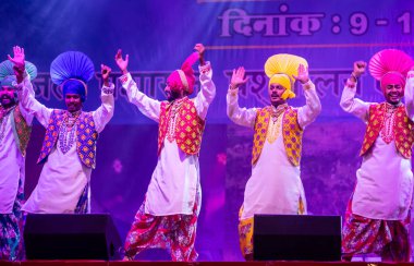 Puşkar, Rajasthan, Hindistan - 11 Kasım 2024: Bhangra, Bhangra grubu, açık hava kültür gecesi renkli etnik elbiseler içinde bhangra dansı yapıyor.