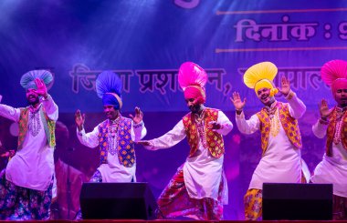 Puşkar, Rajasthan, Hindistan - 11 Kasım 2024: Bhangra, Bhangra grubu, açık hava kültür gecesi renkli etnik elbiseler içinde bhangra dansı yapıyor.