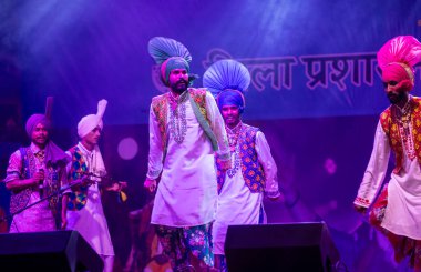 Puşkar, Rajasthan, Hindistan - 11 Kasım 2024: Bhangra, Bhangra grubu, açık hava kültür gecesi renkli etnik elbiseler içinde bhangra dansı yapıyor.