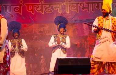 Pushkar, Rajasthan, Hindistan - 11 Kasım 2024: Bhangra, Sih erkek sanatçılar grubu renkli etnik elbiseler içinde bhangra dansı yapıyorlar..