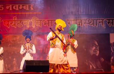 Pushkar, Rajasthan, Hindistan - 11 Kasım 2024: Bhangra, Sih erkek sanatçılar grubu renkli etnik elbiseler içinde bhangra dansı yapıyorlar..