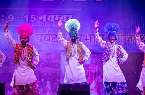 Pushkar, Rajasthan, Hindistan - 11 Kasım 2024: Bhangra, Sih erkek sanatçılar grubu renkli etnik elbiseler içinde bhangra dansı yapıyorlar..