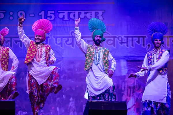 Pushkar, Rajasthan, Hindistan - 11 Kasım 2024: Bhangra, Sih erkek sanatçılar grubu renkli etnik elbiseler içinde bhangra dansı yapıyorlar..