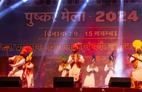 Pushkar, Rajasthan, Hindistan - 11 Kasım 2024: Bhangra, Sih erkek sanatçılar grubu renkli etnik elbiseler içinde bhangra dansı yapıyorlar..