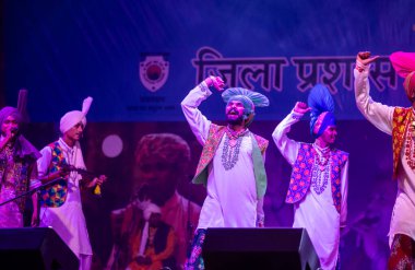 Pushkar, Rajasthan, Hindistan - 11 Kasım 2024: Bhangra, Sih erkek sanatçılar grubu renkli etnik elbiseler içinde bhangra dansı yapıyorlar..