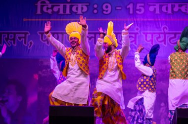 Pushkar, Rajasthan, Hindistan - 11 Kasım 2024: Bhangra, Sih erkek sanatçılar grubu renkli etnik elbiseler içinde bhangra dansı yapıyorlar..