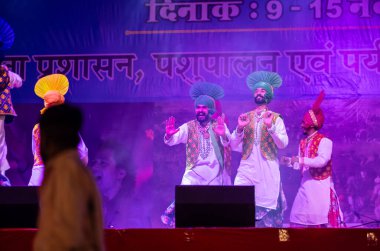 Pushkar, Rajasthan, Hindistan - 11 Kasım 2024: Bhangra, Sih erkek sanatçılar grubu renkli etnik elbiseler içinde bhangra dansı yapıyorlar..