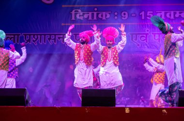 Pushkar, Rajasthan, Hindistan - 11 Kasım 2024: Bhangra, Sih erkek sanatçılar grubu renkli etnik elbiseler içinde bhangra dansı yapıyorlar..