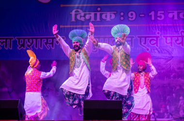 Pushkar, Rajasthan, Hindistan - 11 Kasım 2024: Bhangra, Sih erkek sanatçılar grubu renkli etnik elbiseler içinde bhangra dansı yapıyorlar..