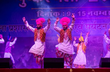 Pushkar, Rajasthan, Hindistan - 11 Kasım 2024: Bhangra, Sih erkek sanatçılar grubu renkli etnik elbiseler içinde bhangra dansı yapıyorlar..