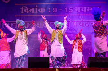 Pushkar, Rajasthan, Hindistan - 11 Kasım 2024: Bhangra, Sih erkek sanatçılar grubu renkli etnik elbiseler içinde bhangra dansı yapıyorlar..