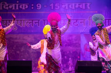 Pushkar, Rajasthan, Hindistan - 11 Kasım 2024: Bhangra, Sih erkek sanatçılar grubu renkli etnik elbiseler içinde bhangra dansı yapıyorlar..