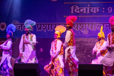 Pushkar, Rajasthan, Hindistan - 11 Kasım 2024: Bhangra, Sih erkek sanatçılar grubu renkli etnik elbiseler içinde bhangra dansı yapıyorlar..