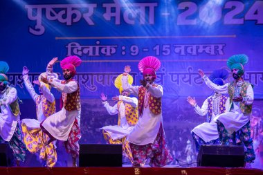 Puşkar, Rajasthan, Hindistan - 11 Kasım 2024: Bhangra, Bhangra grubu, açık hava kültür gecesi renkli etnik elbiseler içinde bhangra dansı yapıyor.