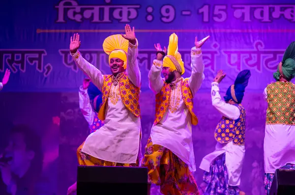 Pushkar, Rajasthan, Hindistan - 11 Kasım 2024: Bhangra, Sih erkek sanatçılar grubu renkli etnik elbiseler içinde bhangra dansı yapıyorlar..