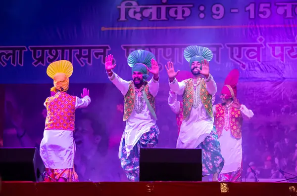 Pushkar, Rajasthan, Hindistan - 11 Kasım 2024: Bhangra, Sih erkek sanatçılar grubu renkli etnik elbiseler içinde bhangra dansı yapıyorlar..