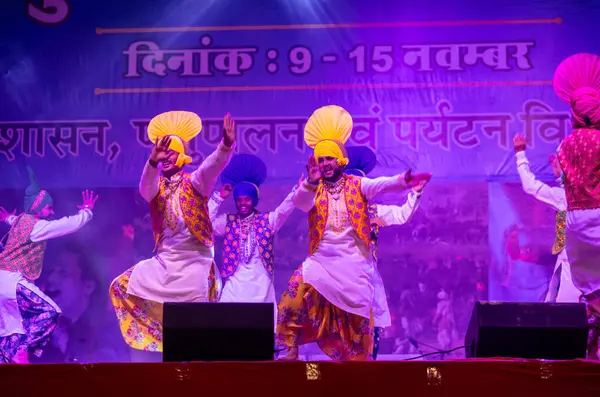 Pushkar, Rajasthan, Hindistan - 11 Kasım 2024: Bhangra, Sih erkek sanatçılar grubu renkli etnik elbiseler içinde bhangra dansı yapıyorlar..