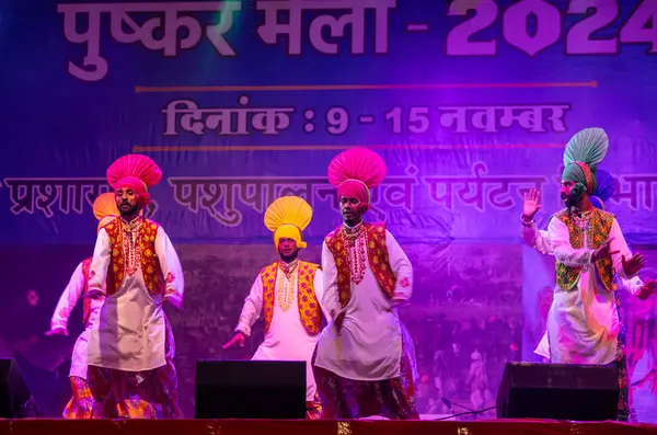 Pushkar, Rajasthan, Hindistan - 11 Kasım 2024: Bhangra, Sih erkek sanatçılar grubu renkli etnik elbiseler içinde bhangra dansı yapıyorlar..