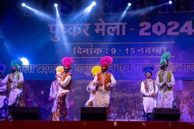 Puşkar, Rajasthan, Hindistan - 11 Kasım 2024: Bhangra, Bhangra grubu, açık hava kültür gecesi renkli etnik elbiseler içinde bhangra dansı yapıyor.