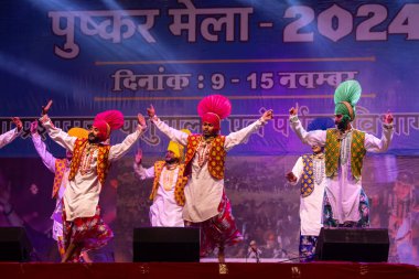 Puşkar, Rajasthan, Hindistan - 11 Kasım 2024: Bhangra, Bhangra grubu, açık hava kültür gecesi renkli etnik elbiseler içinde bhangra dansı yapıyor.