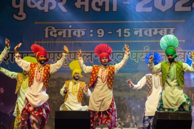 Puşkar, Rajasthan, Hindistan - 11 Kasım 2024: Bhangra, Bhangra grubu, açık hava kültür gecesi renkli etnik elbiseler içinde bhangra dansı yapıyor.