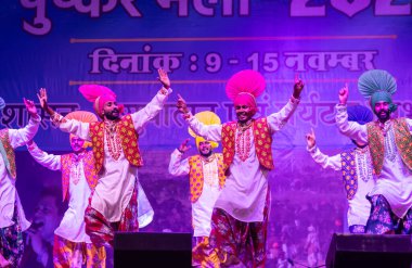 Puşkar, Rajasthan, Hindistan - 11 Kasım 2024: Bhangra, Bhangra grubu, açık hava kültür gecesi renkli etnik elbiseler içinde bhangra dansı yapıyor.