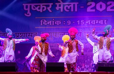 Puşkar, Rajasthan, Hindistan - 11 Kasım 2024: Bhangra, Bhangra grubu, açık hava kültür gecesi renkli etnik elbiseler içinde bhangra dansı yapıyor.