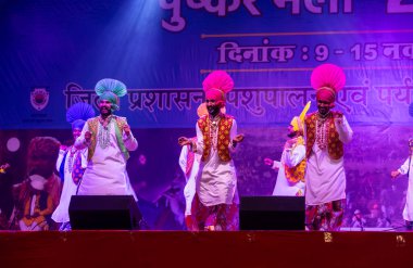 Puşkar, Rajasthan, Hindistan - 11 Kasım 2024: Bhangra, Bhangra grubu, açık hava kültür gecesi renkli etnik elbiseler içinde bhangra dansı yapıyor.