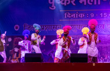 Puşkar, Rajasthan, Hindistan - 11 Kasım 2024: Bhangra, Bhangra grubu, açık hava kültür gecesi renkli etnik elbiseler içinde bhangra dansı yapıyor.